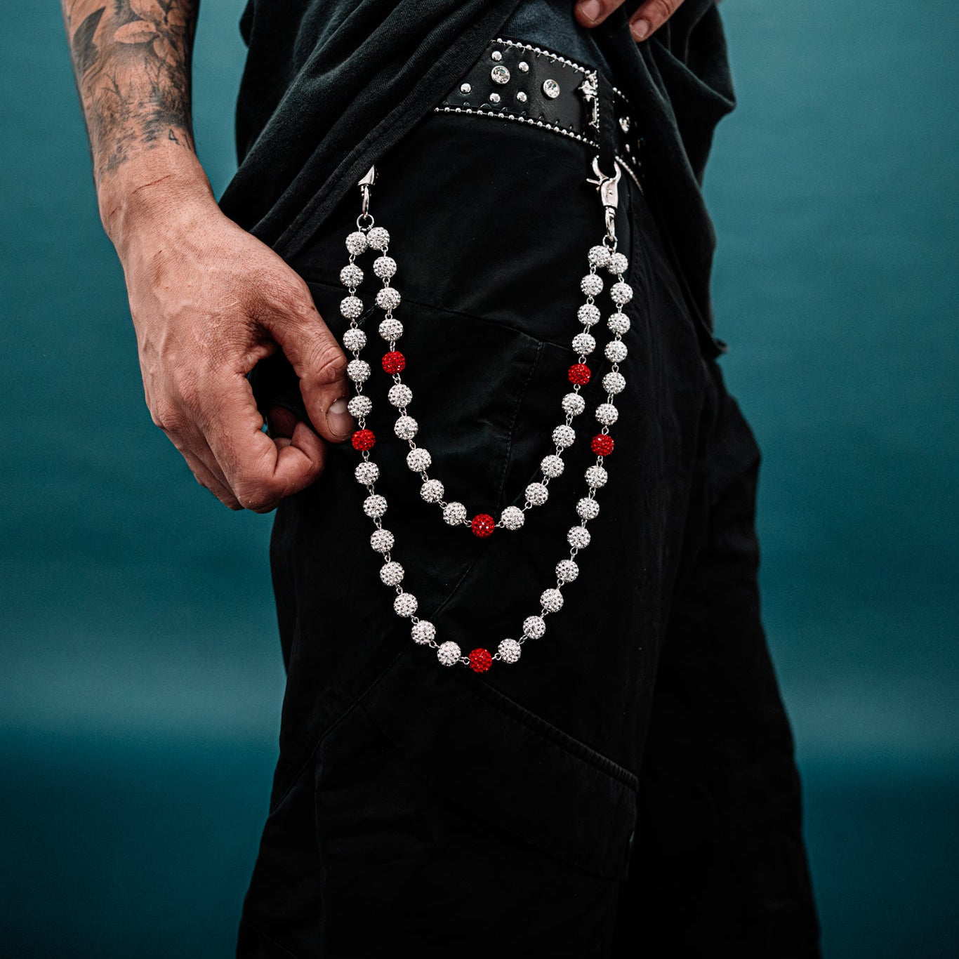 Person wearing a black outfit with a necklace against a blue background