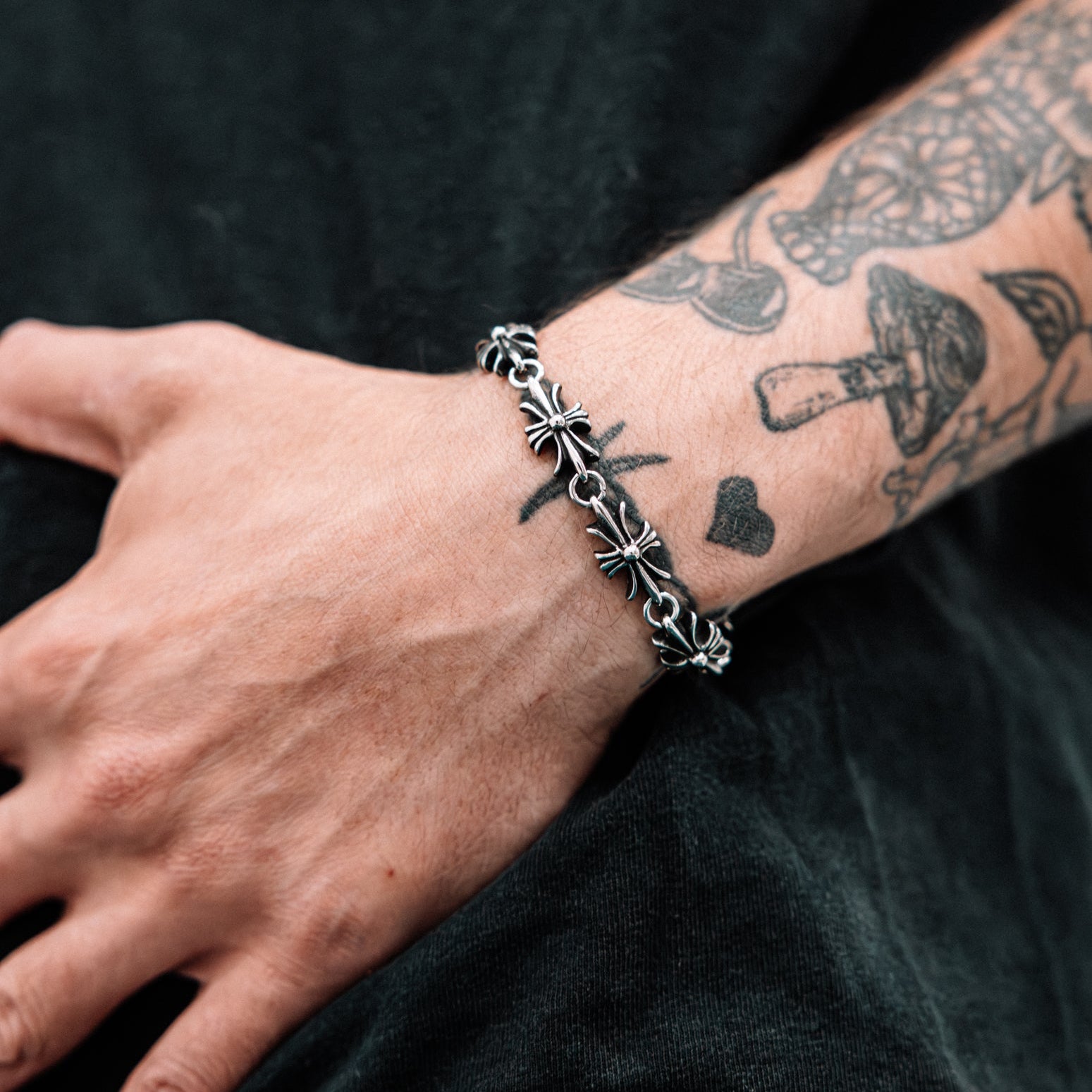 Close-up of a wrist wearing a silver bracelet with a dark background
